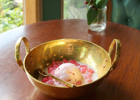 Téléchargez les photos : Dessert thaïlandais appelé Tub Tim Grob ou Mock Pomegranate dans du lait de coco servi avec crème glacée dans un bol en laiton doré - en image libre de droit