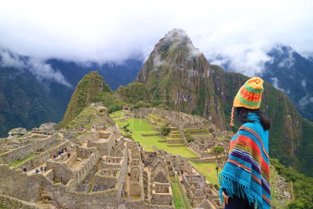 Photo for Woman in Poncho and Andean Hat Visiting the Amazing Ancient Inca Citadel of Machu Picchu, UNESCO World Heritage Site in Cusco Region, Peru, South America - Royalty Free Image