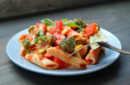 Téléchargez les photos : Cueillette à la fourchette Penne aromatisée aux légumes rôtis en sauce tomate basilic - en image libre de droit