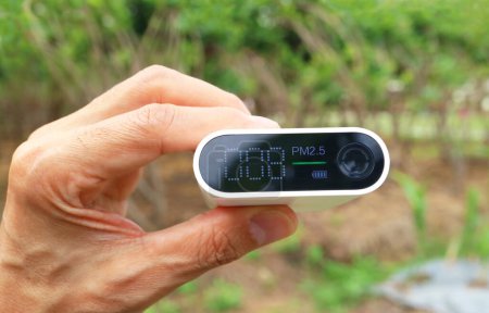 Téléchargez les photos : Main d'homme tenant un capteur de pollution atmosphérique mesurant la qualité de l'air dans le jardin - en image libre de droit