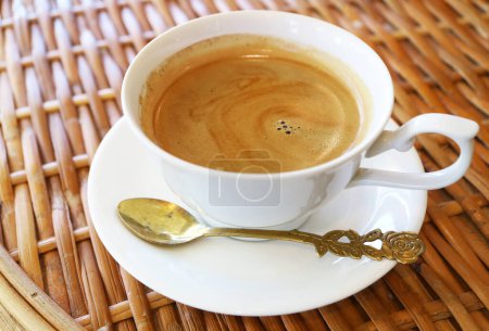 Photo for Cup of hot coffee with spoon isolated on rattan table - Royalty Free Image