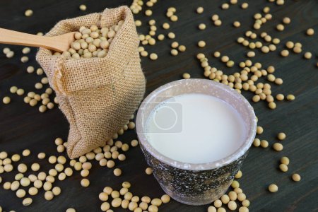 Téléchargez les photos : Coupe de lait de soja avec un sac de toile de jute de soja sur une table en bois - en image libre de droit