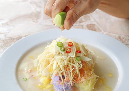 Téléchargez les photos : Pressage à la main de jus de chaux frais dans Khanom Chin Sao Nam, une délicieuse soupe de salade de vermicelles de riz thaïlandais - en image libre de droit