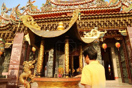 Foto de Visitante colocando palos de incienso en el quemador en un templo budista chino - Imagen libre de derechos