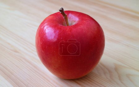 Closeup of a fresh ripe red apple isolated on wooden table