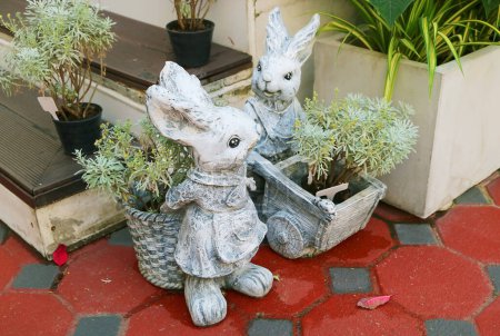 Paire de sculptures adorables de lapin de Pâques en pierre dans le patio