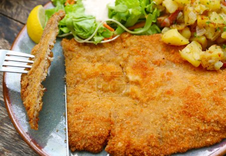 Closeup of Knife Cutting Thin and Crispy Delicious Schnitzel