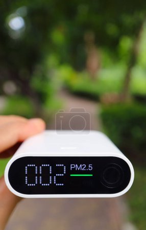 Hand holding an air pollution sensor measuring air quality in the garden