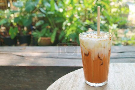 Vaso de té helado tailandés de riego bucal aislado en la mesa de jardín