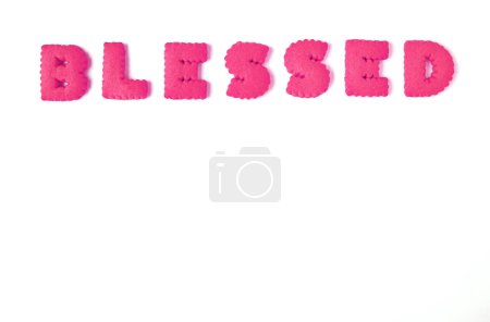 Text BLESSED spelled with rose pink alphabet shaped cookies on white background