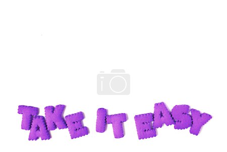Vibrant purple alphabet shaped cookies spelling the word TAKE IT EASY on white background