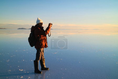 Reisende schießen Fotos über den erstaunlichen Spiegeleffekt der Uyuni-Salzebenen bei Sonnenuntergang, Bolivien, Südamerika