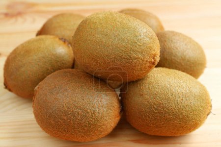 Closeup of pile of fresh kiwi fruits on wooden table