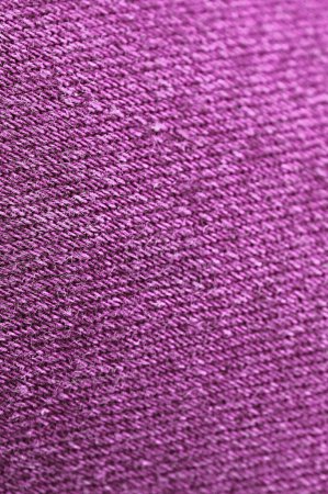 Primer plano de la textura de la tela de los pantalones vaqueros de color púrpura Magenta con enfoque selectivo