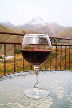 Photo for Glass of Red Wine on a Table with Mount Kazbek of Georgia in the Backdrop - Royalty Free Image