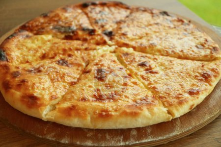 Closeup of Freshly Baked Khachapuri Imeruli or Cheese-filled Georgian Flatbread on Wooden Breadboard