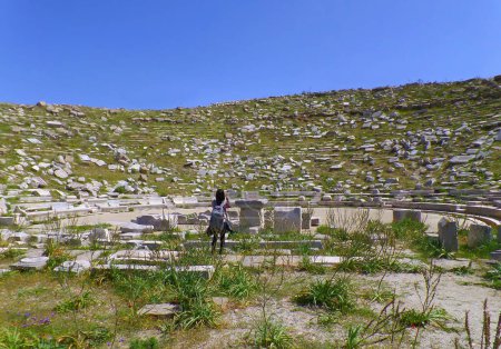 Viajero femenino que visita el antiguo teatro de Delos, sitio arqueológico asombroso en la isla de Delos, Mykonos, Grecia