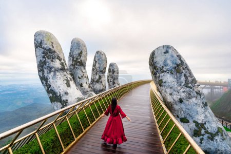 Viajante joven en vestido rojo disfrutando en el puente de oro en las colinas de Bana, Danang Vietnam, Viajar concepto de estilo de vida