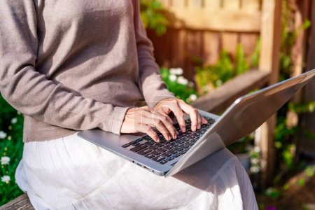 Junge Frau mit Laptop und Entspannung im Garten, Moderner Lebensstil