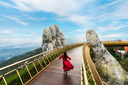 Viajante joven en vestido rojo disfrutando en el puente de oro en las colinas de Bana, Danang Vietnam, Viajar concepto de estilo de vida