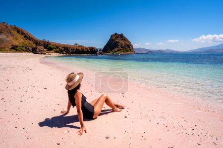 Joven turismo femenino disfrutando de la playa tropical de arena rosa con agua turquesa clara en las islas Komodo en Indonesia
