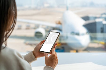 Foto de Joven mujer asiática viajero usando el teléfono inteligente mientras espera su vuelo en el aeropuerto - Imagen libre de derechos