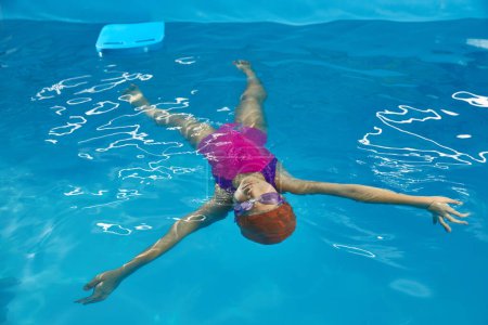 Foto de Niña acostada en el agua descansando en la piscina cubierta - Imagen libre de derechos