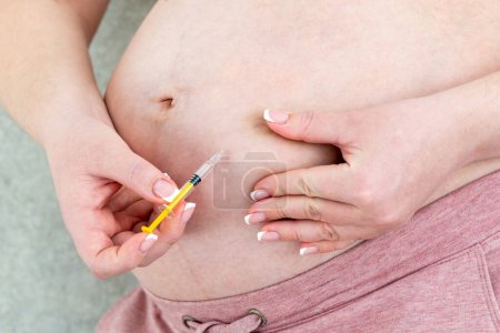 Téléchargez les photos : Concept d'anticoagulants. Femme enceinte faisant l'injection dans son ventre - en image libre de droit
