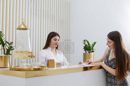 Foto de Recepcionista femenina en recepción con un cliente - Imagen libre de derechos