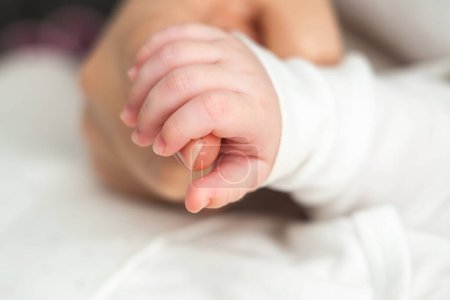 Foto de Primer plano de un bebé recién nacido soñando, apretado de la mano de las madres, comunica amor puro y confianza - Imagen libre de derechos