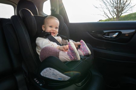Bebé alegre y sonriente en un asiento de coche disfrutando de un paseo en coche. Concepto de viajar con seguridad con niños