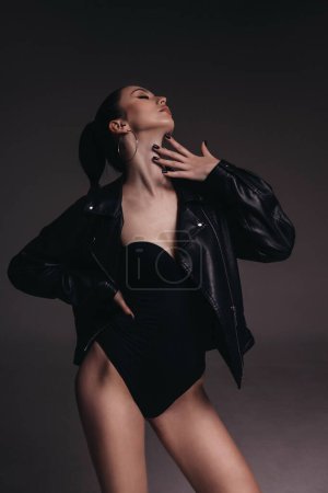 Foto de Foto de moda de mujer hermosa con cabello oscuro en ropa elegante y chaqueta de cuero negro - Imagen libre de derechos