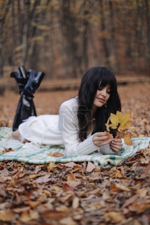 Téléchargez les photos : Mode photo extérieure de belle femme aux cheveux foncés dans des vêtements élégants et accessoires posant dans la forêt d'automne - en image libre de droit