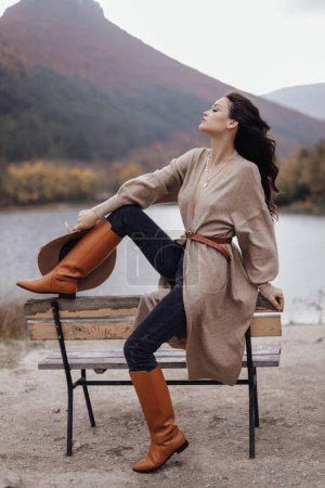 Téléchargez les photos : Fashion outdoor photo of beautiful woman with dark hair in elegant outfit posing on the road in mountains - en image libre de droit