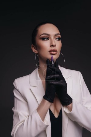 Photo for Fashion photo of beautiful woman with dark hair in medical gloves posing in studio with cosmetologist tools - Royalty Free Image