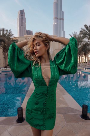 Foto de Fashion outdoor photo of beautiful woman with blond hair in elegant green dress posing in Arab countryside - Imagen libre de derechos
