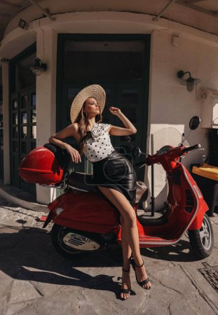 Téléchargez les photos : Mode photo extérieure de belle femme aux cheveux foncés dans une robe élégante avec des accessoires posant sur moto - en image libre de droit
