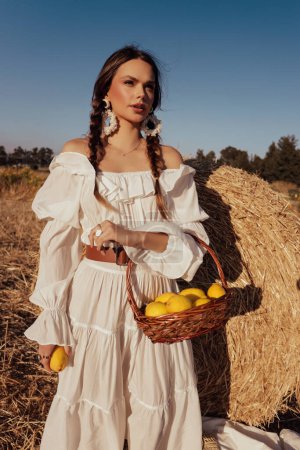 Photo for Fashion outdoor photo of beautiful woman with dark hair in elegant white dress with accessories posing in hayloft - Royalty Free Image