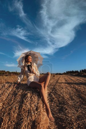 Foto de Foto de moda al aire libre de la mujer hermosa con el pelo oscuro posando en el pajar - Imagen libre de derechos