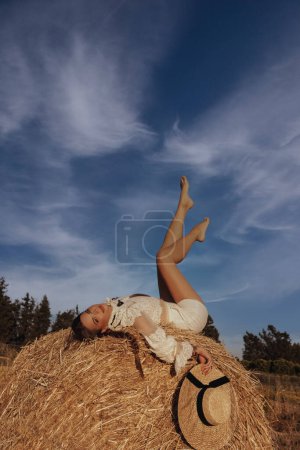 Téléchargez les photos : Photo extérieure de mode de belle femme aux cheveux foncés posant dans un grenier à foin - en image libre de droit