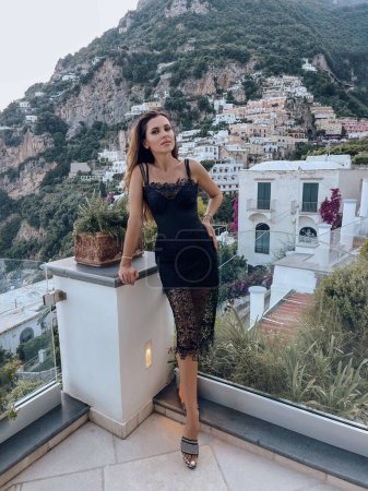 Photo for Fashion travel photo of beautiful woman with dark hair in elegant clothes posing against the backdrop of the city Positano in Italy - Royalty Free Image