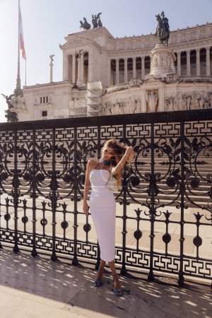 Foto de Foto de moda al aire libre de la mujer hermosa con el pelo rubio en vestido elegante y accesorios viajes en Italia - Imagen libre de derechos
