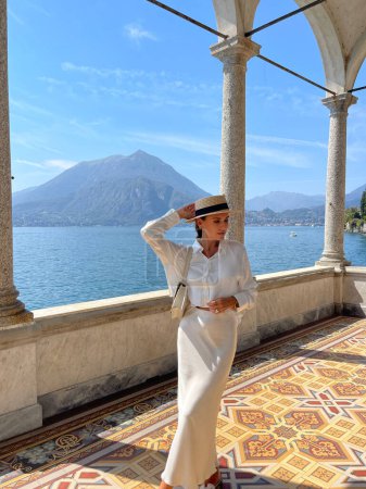 Téléchargez les photos : Photo de mode en plein air de belle femme aux cheveux foncés dans des vêtements élégants posant dans une villa luxueuse au lac de Côme en Italie - en image libre de droit