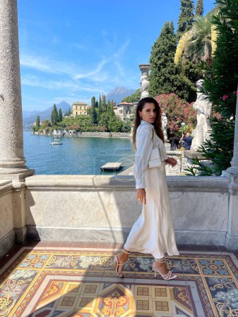 Photo for Fashion outdoor photo of beautiful woman with dark hair in elegant clothes posing in luxurious villa at Como lake in Italy - Royalty Free Image
