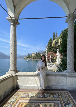 Foto de Foto de moda al aire libre de la hermosa mujer con el pelo oscuro en ropa elegante posando en lujosa villa en el lago Como en Italia - Imagen libre de derechos