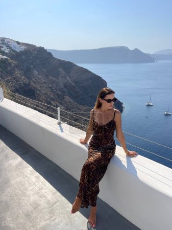 Téléchargez les photos : Mode photo extérieure de belle femme aux cheveux foncés dans des vêtements élégants avec accessoire voyageant autour de l'île de Santorin - en image libre de droit