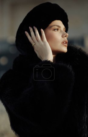 Foto de Foto de moda de la hermosa mujer eslava en abrigo de piel negro y sombrero posando al aire libre - Imagen libre de derechos