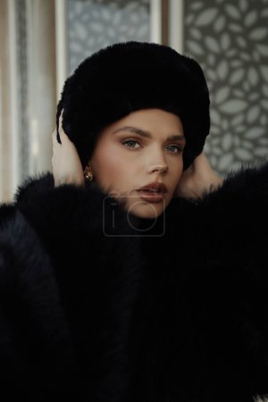 Téléchargez les photos : Photo de mode de belle femme esclave en manteau de fourrure noire et chapeau posant en plein air - en image libre de droit