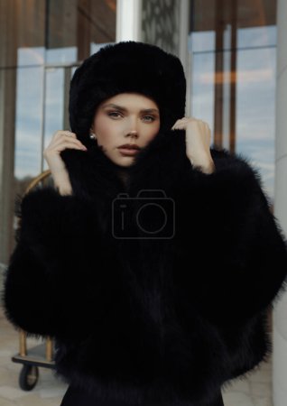 Photo for Fashion photo of beautiful slavic woman in black fur coat and hat posing outdoor - Royalty Free Image
