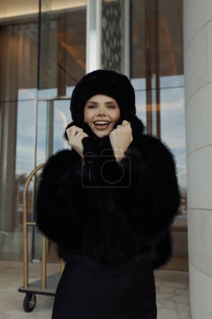 Téléchargez les photos : Photo de mode de belle femme esclave en manteau de fourrure noire et chapeau posant en plein air - en image libre de droit
